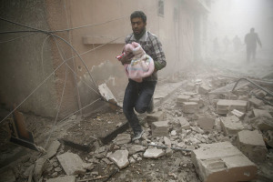 A Syrian man carries a baby wrapped in a blanket following air strikes on the town of Douma in the eastern Ghouta region, a rebel stronghold east of the capital Damascus, on December 13, 2015. At least 28 civilians were killed in heavy bombardment of the besieged Syrian rebel stronghold, including near a school, according to the Syrian Observatory for Human Rights. AFP PHOTO / SAMEER AL-DOUMY